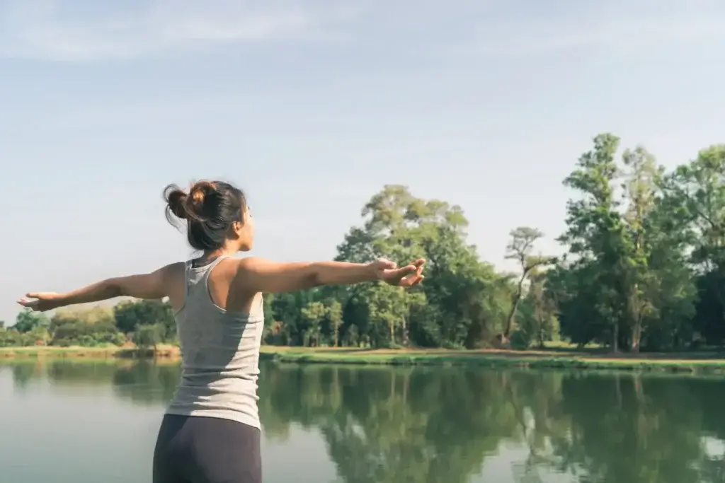 Woman with arms outstretched by a lake, symbolizing health, balance, and nature in Nanaimo.
